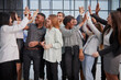 © Katsiaryna - Excited multinational employees celebrating team victory giving high five gathered in office,