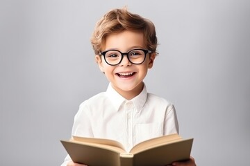 Wall Mural - Kid boy wear glasses reading a book publication portrait smile.