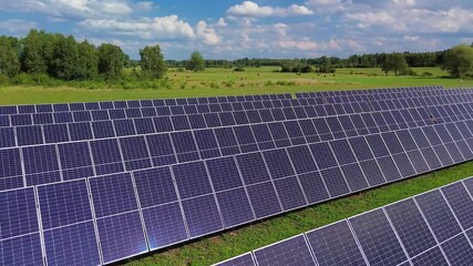 aerial view photovoltaic panels with trackers on green field with trees and forest in poland. blue s