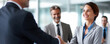 © iwaart - Business professionals engage in a handshake during a corporate meeting at an office building
