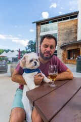 Wall Mural - A man sits at a table with a dog on his lap