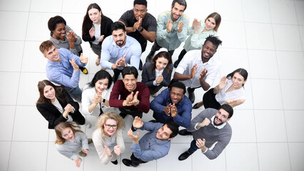 Diverse group of happy young people looking up and smiling at camera.