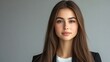 © CinimaticWorks - professional corporate portrait of a young woman in sleek business attire with long straight hair against a neutral gray background ideal for executive leadership and business success