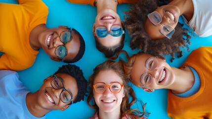 Diverse Group of Happy Young People Lying in a Circle on Blue Background Wearing Colorful Glasses and Smiling