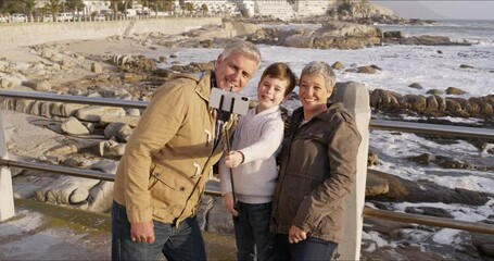 Poster - Grandparents bonding, taking a selfie with a happy child at the sea together on a day trip outdoors. Carefree, lovely and senior man, woman and little grandson smiling for a family photo at the beach