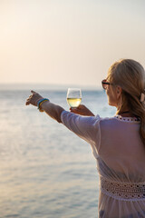 Wall Mural - Woman with a glass of wine at the sea. Selective focus.