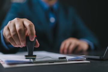 Poster - Close-up Of A Person's Hand Stamping With Approved Stamp On Document At Desk, notary or business people work from home, isolated for coronavirus COVID-19 protection