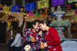 © Marcos - Mexican young couple or friends having fun in posada celebration for Christmas in Mexico Latin America, hispanic people