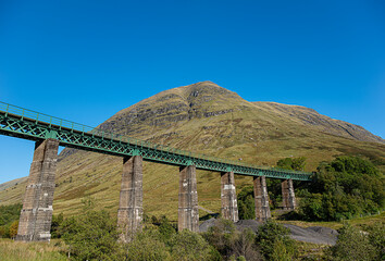 Landscape photography of train viaduct in the valley Glen Auch, railway bridge, mountain Beinn Mhanach, Scotland, UK, trail, rocky, sunlight with blue sky, travel, hiking, hill walking