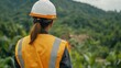 © sunchai - An engineer in a safety helmet overlooks a lush green landscape.