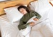 © Wavebreak Media - Sleeping peacefully, woman resting in bed with white sheets and green sweater