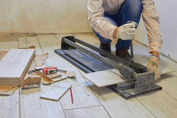 cut the tile with a cutter, construction worker cuts tiles on the floor with a tool