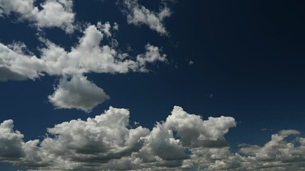 Wall Mural - time lapse of white to grey cumulus clouds moving towards the viewer in a dark blue sky. only the sk