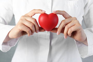 Canvas Print - Doctor holding red heart on grey background, closeup