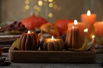 Wall Mural - Burning candles in shape of pumpkins and autumn decor on wooden table