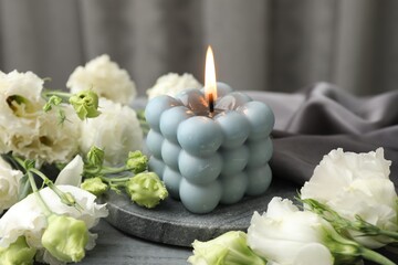 Poster - Burning bubble candle and beautiful flowers on table, closeup