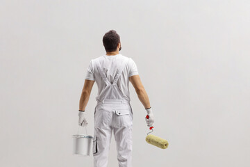 Wall Mural - Rear view shot of a painter holding a bucket and a paint roller