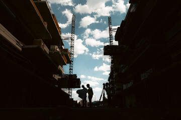 Cadastre and land registration engineers in a construction site. Topographic industry and cadastre concept photo. Silhouette of architects and engineers while discussing about a project.