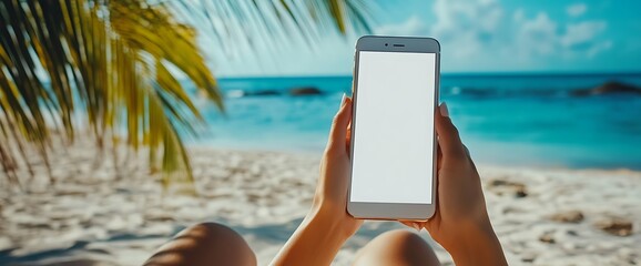 Wall Mural - Woman's hands holding a smartphone on a tropical beach with blue water and white sand.