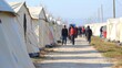 © Mykhailo Podolian - People walking between tents in a refugee camp during a sunny day in early spring