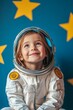 © Oscar - Little child girl in an astronaut costume is playing and dreaming of becoming a spaceman. Portrait of funny kid on a background of bright blue wall with yellow stars
