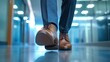 © Pannin - Close-up of a businessman feet in polished brown shoes, hurrying across a sleek office corridor. The blurred background of a modern office shows the urgency of being late to a meeting.