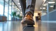 © Pannin - Close-up of a businessman feet in polished brown shoes, hurrying across a sleek office corridor. The blurred background of a modern office shows the urgency of being late to a meeting.