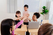 © twinsterphoto - Primary School Children Demonstrate Inclusivity and Mutual Support through Enthusiastic High Five in Modern Classroom