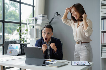 Wall Mural - Business team feeling excited and raising their arms in the air while looking at a laptop screen in the office