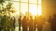 © kept - Professionals networking at a business event in a modern venue, backlit by the golden glow of a sunset through large windows.