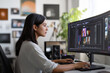 © Olena - A young Indian woman editor sits at a desk in front of a monitor. Brunette woman Video maker in a white T-shirt edits a video in the studio.