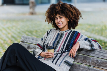 Wall Mural - young African American business woman holding coffee cup in city of Latin America, Hispanic financial and caribbean people with skyscraper background