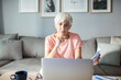 © Marko Geber - Senior woman managing finances on laptop at home