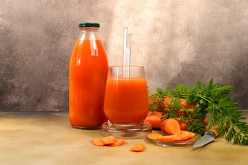 Fresh natural carrot juice or smoothie, Detox drink in glass bottle and glass, carrot slices on concrete background, helps weight loss, healthy lifestyle and vegetarian diet concept,