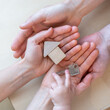 © Michael - A child's hand reaches for a door key next to a small wooden toy house that lies in the open hands of its parents.