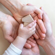 © Michael - One of the child's hands grabs a small wooden toy house in the open hands of its parents.