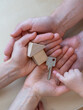 © Michael - A child hand points to a front door key next to a small wooden toy house in the open hands of his parents.