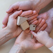 © Michael - A child's hand points to a front door key next to a small wooden toy house in the open hands of his parents.