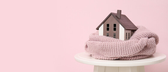 Sticker - Decorative house with scarf on stool against pink background. Winter heating concept