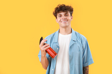 Canvas Print - Handsome young man with bottle of hair spray on yellow background