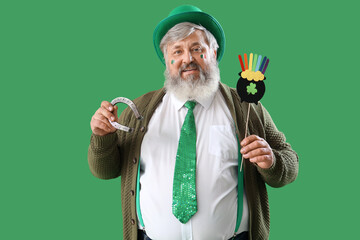 Wall Mural - Mature man with horseshoe and decor on green background. St. Patrick's Day celebration