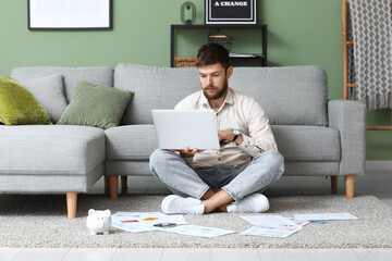 Poster - Young man in debt using laptop on carpet at home