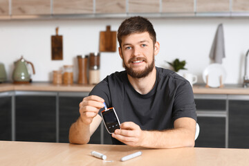 Wall Mural - Diabetic young man using glucometer in kitchen