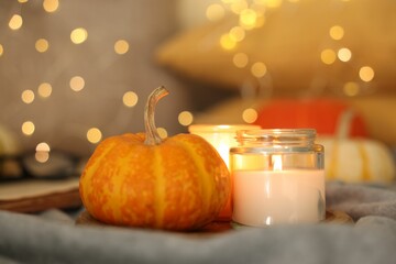 Sticker - Burning candles and pumpkin on grey cloth against blurred lights, closeup. Autumn atmosphere