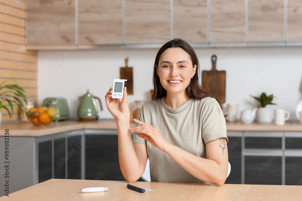 Diabetic young woman with glucometer at table in kitchen