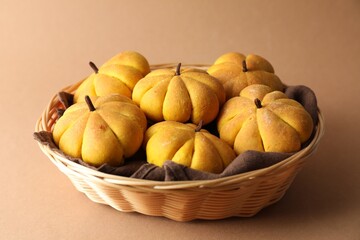 Wall Mural - Wicker basket with tasty pumpkin shaped buns on beige background, closeup