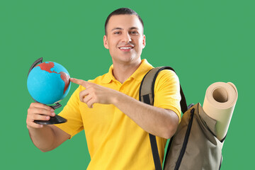 Poster - Male tourist with globe and bag on green background