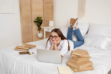 Poster - Happy female student with laptop, tablet and books studying at home