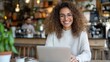 © Lens Legacy - A woman works diligently on her laptop in a chic café decorated with green plants, embodying modernity and a tranquil ambiance, blending professionalism with personal comfort.