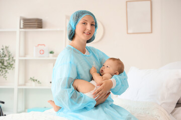 Sticker - Young mother with her newborn baby sitting on bed in maternity hospital